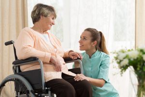 Elderly woman on wheelchair in nursing home with her care assistant